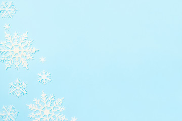 Fototapeta na wymiar Christmas or winter composition. Snowflakes decoration on blue pastel background. Flat lay, top view, copy space.