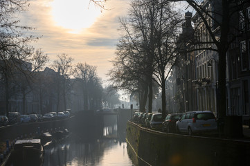 Golden morning sun shines on a canal in a Dutch town.