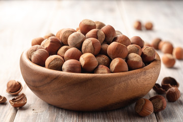 Hazelnuts in bowl on white wooden background. Selective focus.