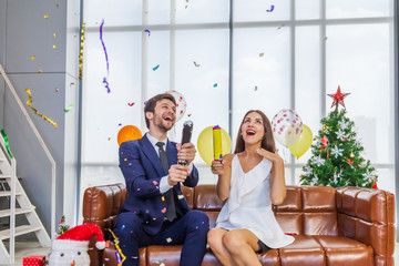 Romantic couples celebrate Christmas on the sofa with happy faces and are fireworks, party poppers to celebrate. Christmas and New Year concept