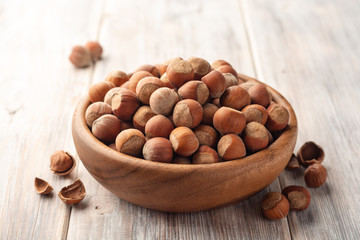 Hazelnuts in bowl on white wooden background. Selective focus.