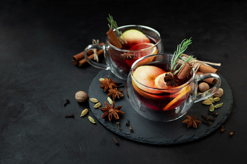 Two cups of Christmas mulled wine or punch with spices and lemon slices on dark wooden background. Christmas or New Year celebration concept