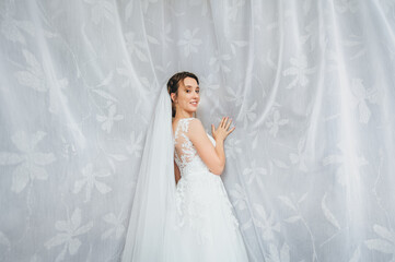 Wedding portrait of a beautiful and young bride in white curtains and fabrics. Cute bride with a...