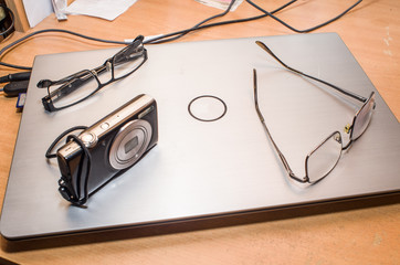 Addition laptop on the table, off, on it are two glasses and is a portable camera, close-up, copy...