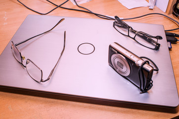 Addition laptop on the table, off, on it are two glasses and is a portable camera, close-up, copy...