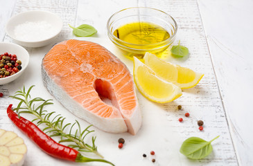 Fresh raw salmon steak with lemon, olive oil and spices on white wooden background. Ingredient for making healthy dinner. Healthy diet concept. 