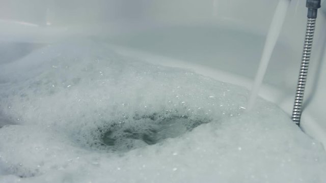 Water running in to the bathtub, fulled bathtub. Preparing bath for relax.