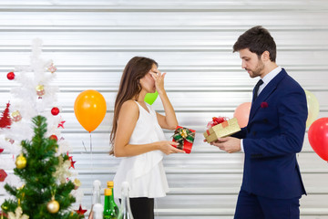 Romantic lovers smiling and exchanging gifts in the midst of a festive celebration that decorated with balloons. Concept of New Year, Christmas, Woman's Day, Valentine Party.