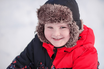 Portrait of smiling boy in winter. Warm clothes, fur hat, winter sport. Happy child on a snow background. Face closeup.