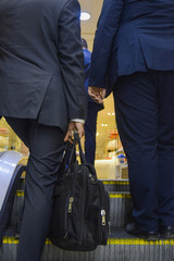 a group of three busy businessmen dressed in suits climbing up escalators indoors