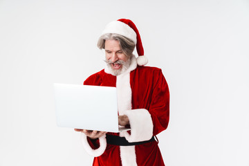 Portrait of delighted old man holding and using laptop