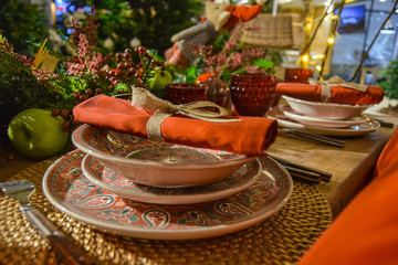 Christmas decoration with coloured crockery, black and silver cutlery, red glasses and table centerpiece
