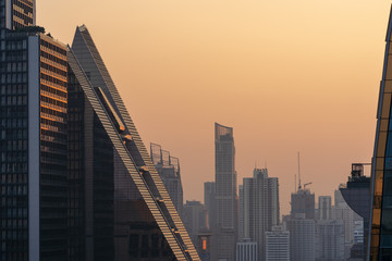 Obraz premium Sunrise at morning at Bangkok metropolis. Building in big city. Shade for shadow orange light.