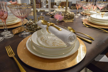 Christmas decoration with white crockery, golden cutlery, rose glasses and table centerpiece