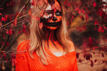 Young blonde girl with halloween face art posing outdoor.  Helloween celebration concept.