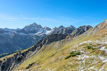 Beautiful alpine landscape above the tree line in fall with some snow under blue sky. Hochvogel mountain in the background. Allgau Alps, Tirol, Austria