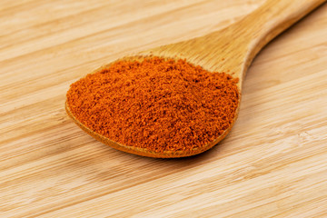 Spoon full of Chili Powder on a wooden background