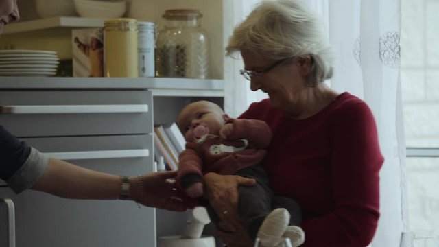 Grandmother Holding Infant and Smling
