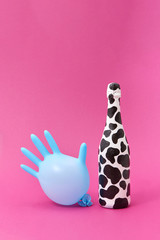 Balloon rubber glove with painted white bottle with black spots.