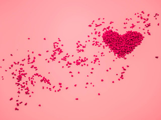 Closeup of red heart shape of small gravel on pink pastel color background. Love, valentine, romance, wedding and honeymoon concept and idea.