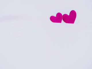 Closeup of vivid and vibrant two pink heart shape stickers on white wrinkled sheet bed cover cotton...