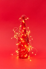 Painted red wine bottle covered Christmas garland with lights.