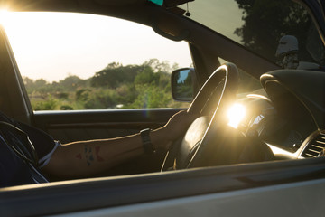 Naklejka premium Young man driving a car with sunset.