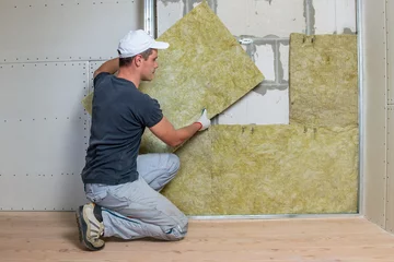 Fotobehang Worker insulating a room wall with mineral rock wool thermal insulation. © bilanol
