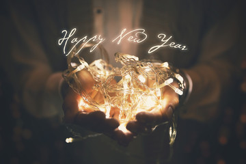 happy new year greeting card - led lights garland glowing in woman hands - Powered by Adobe