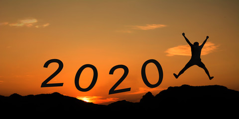 sunset with mountain silhouette and man jump on new year 2019 cross to 2020