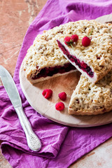 Homemade berry shortcrust pie with crumble on wooden board
