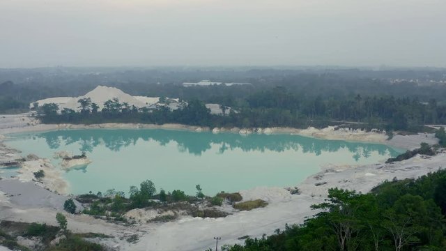 Aerial flyover with dolly zoom of Kaolin big lake mine pit, Bangka Island, Indonesia, tin mineral mine filled with rainwater 