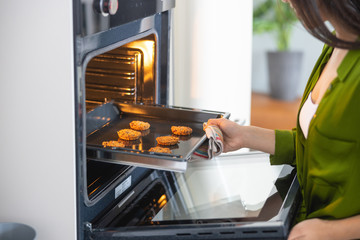 Young Asian housewife opening the convection oven - Powered by Adobe