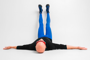Fashion portrait of stylish man in blue tights and indigo boots stretching and exercising over...