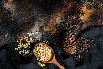 Pine nuts in the spoon and pine nut cone. Organic food. Black background. Top view. Space for text