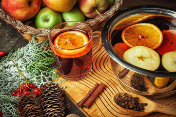 Hot drink mulled wine with citrus, apples and spices in a saucepan