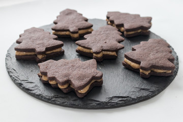 homemade chocolate chip cookies with a caramel layer in the shape of a Christmas tree on a black tray