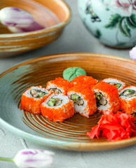 plate of california sushi rolls topped with red tobiko served with ginger