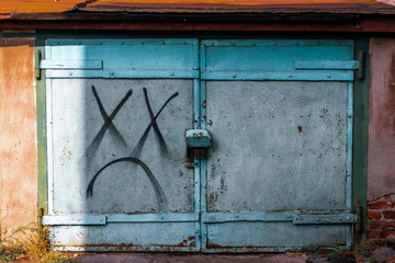 Blue iron gate with a lock. Closed iron gates with a dead emoticon painted on them