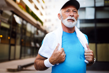 Portrait of athletic mature man after run. Handsome senior man resting after jog at the park