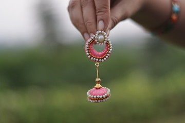 Holding Hand made colorful Earrings with blurred background
