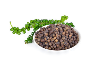 dried black pepper seeds in white ceramic bowl and fresh peppercorn on white background