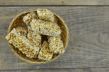 Cereal bars in bamboo basket on wooden background.