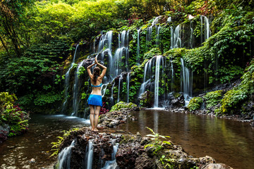 Woman standing on the rock, practicing yoga. Young woman raising arms with namaste mudra near...