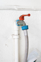 water tap with rubber band on white wall