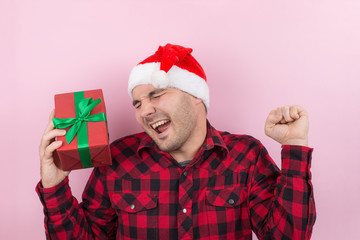 Happy surprised man in a red hat holding a gift with admiration on his face. Positive human...