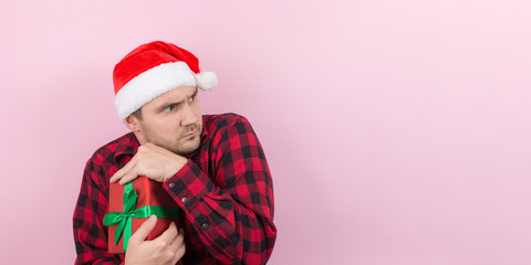 A thief in a red hat, stole someone else's Christmas gifts. Angry character, negative human emotions. Pink background, copy space.