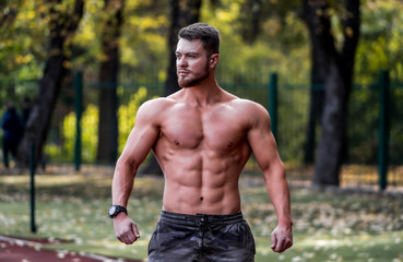 Muscular shirtless man fitness model posing outdoor in a sunny sport yard. Nice muscular body. Half weist photo. Closeup.