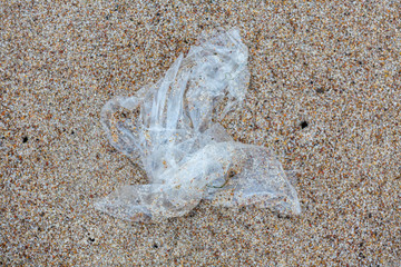 Environmental pollution - a plastic foil, lying on the beach as waste
