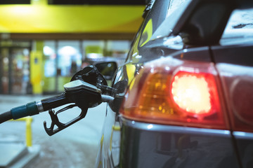 Black fuel nozzle in the car gas tank close up in winter.